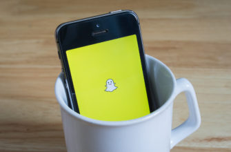 Apple iPhone5s in a mug showing its screen with Snapchat logo