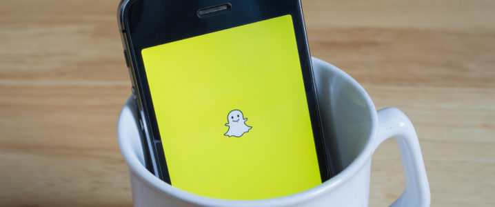 Apple iPhone5s in a mug showing its screen with Snapchat logo