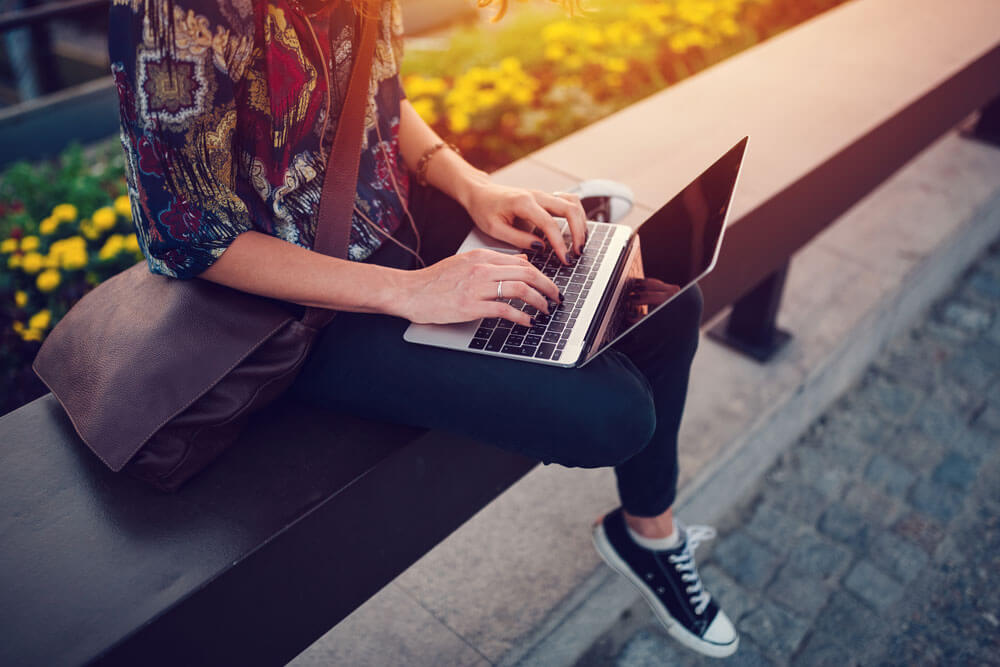 Girl sitting on a bench and working with laptop